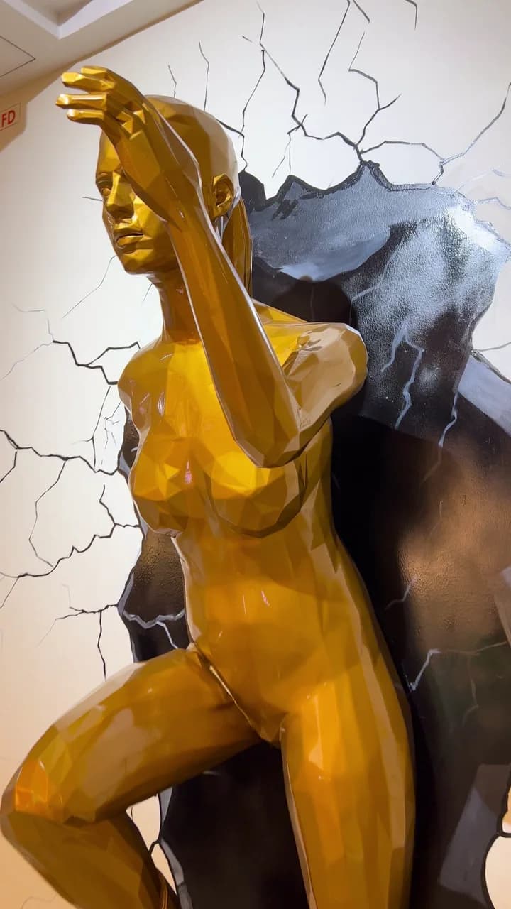 From below: her raised arm and the faceted gold catching the light.
