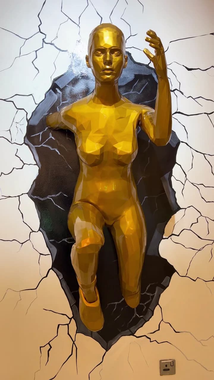 The statue from in front, one hand raised, the broken edge of the wall round her.