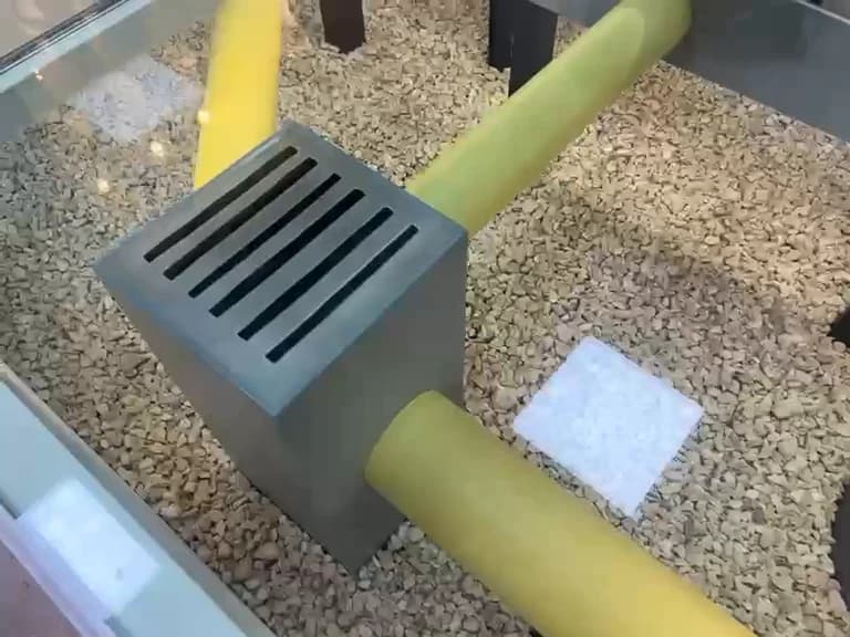 شبكة تصريف في الشارع والأنبوب الأصفر الذي تغذّيه، في الحصى تحت الزجاج.